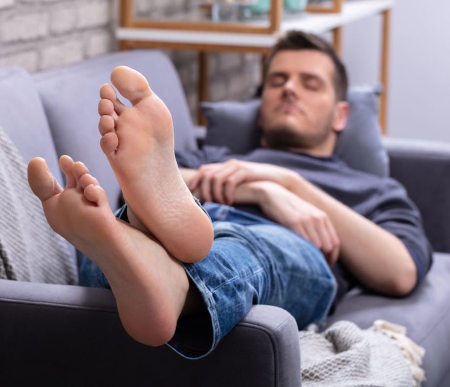 A man resting on a couch with his feet up